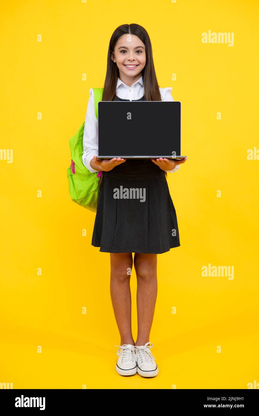 Teen schoolgirl hold laptop on isolated studio background. Cchool ...
