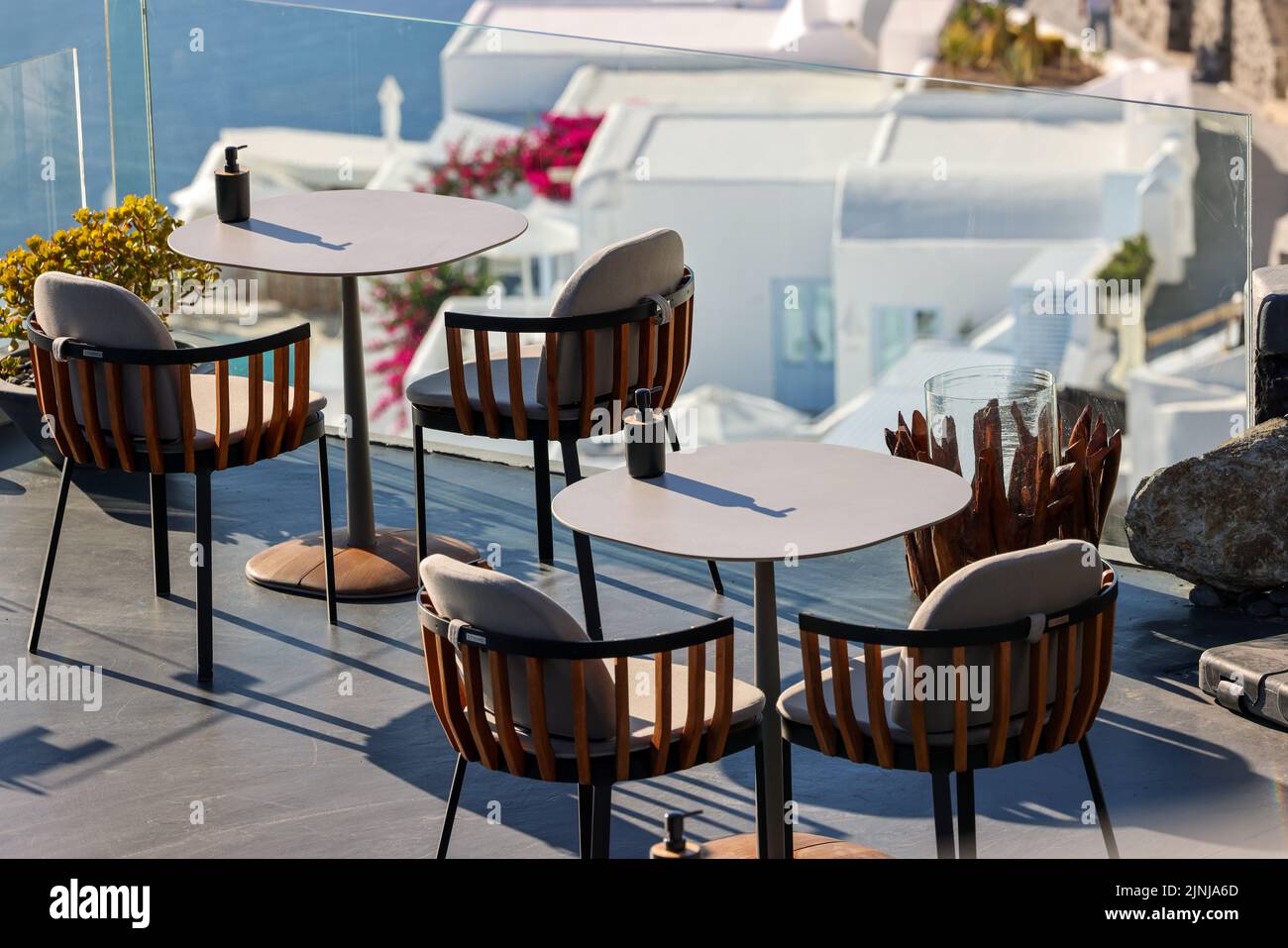 Tables on the restaurant terrace with a picturesque view of the sunset in Imerovigli. Santorini, Greece. Stock Photo