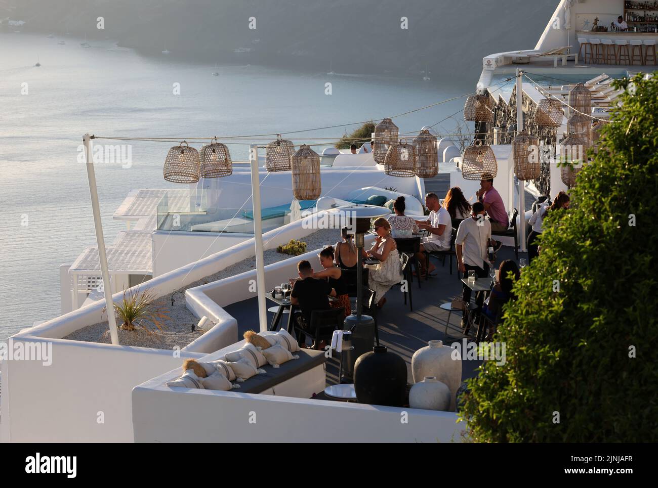 Imergovigli, Santorini, Greece - June 29, 2021: Tables on the restaurant terrace with a picturesque view of the sunset in Imerovigli. Santorini, Greec Stock Photo