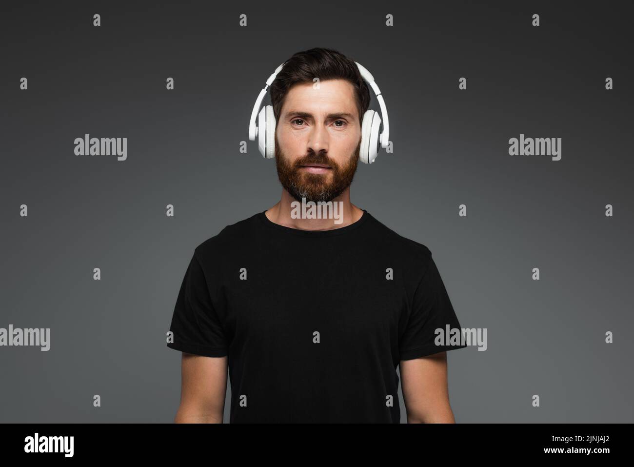bearded man in wireless headphones listening music isolated on grey,stock image Stock Photo