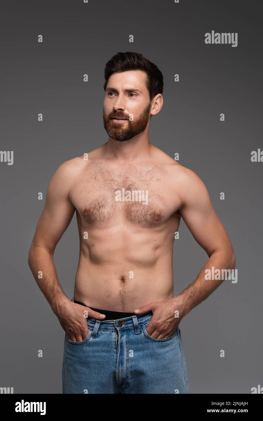 shirtless and bearded man with hair on chest posing with hands in pockets isolated on grey,stock image Stock Photo