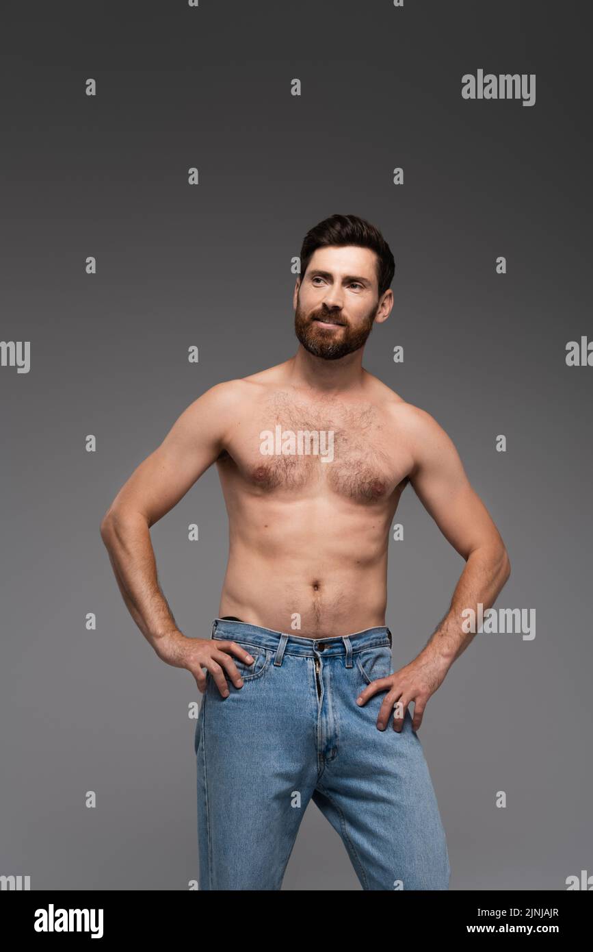 shirtless man with beard posing in denim jeans and smiling isolated on grey,stock image Stock Photo