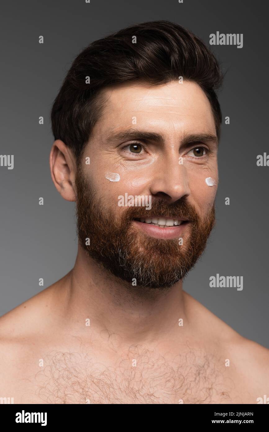portrait of bearded man with cream on face smiling isolated on grey,stock image Stock Photo