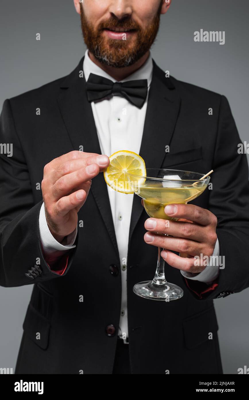 cropped view of bearded man in suit holding glass with cocktail isolated on grey,stock image Stock Photo