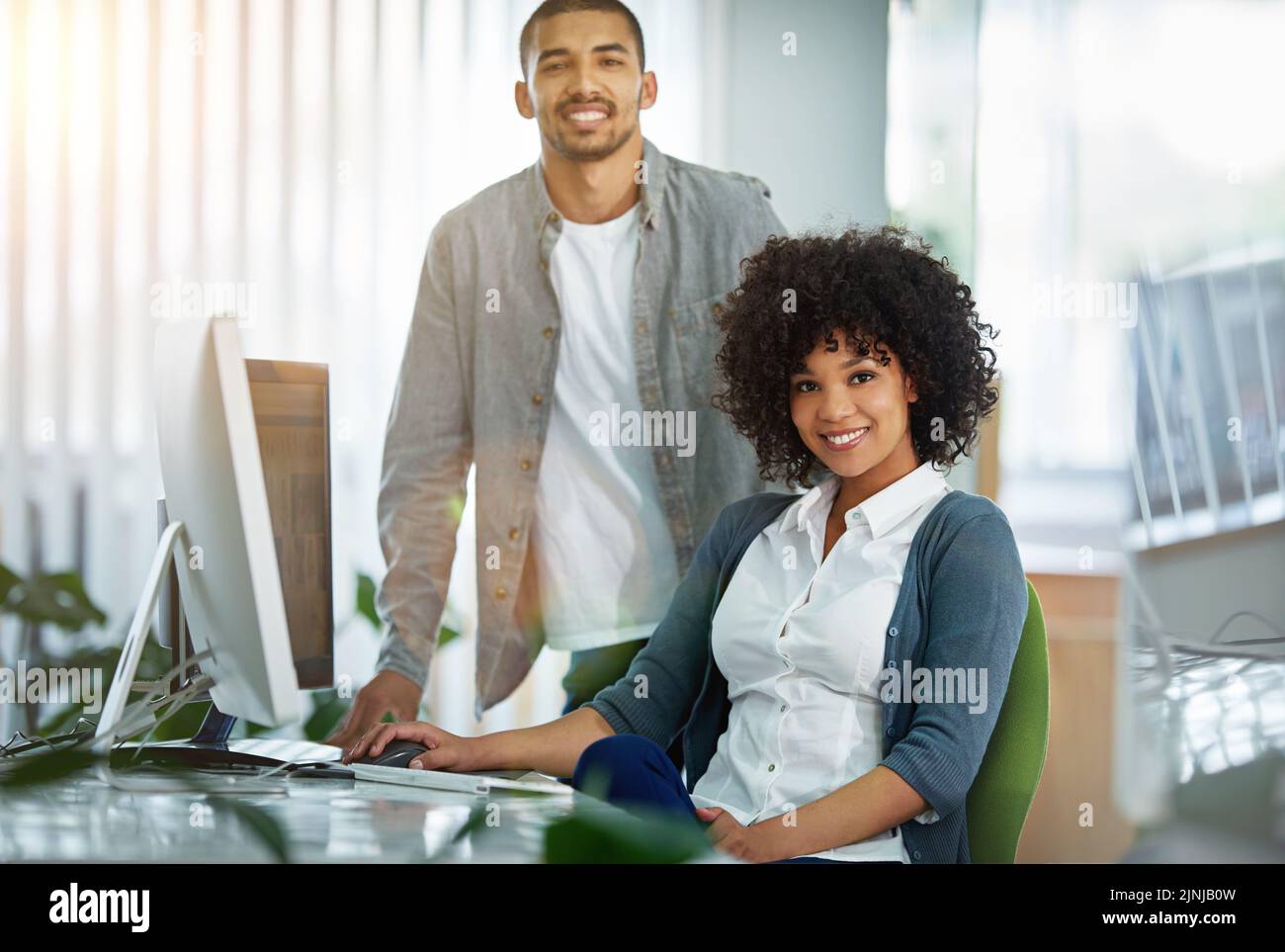 Happy manager or leader helping an employee on a computer to plan ideas or business growth strategy. African female intern or trainee working for a Stock Photo