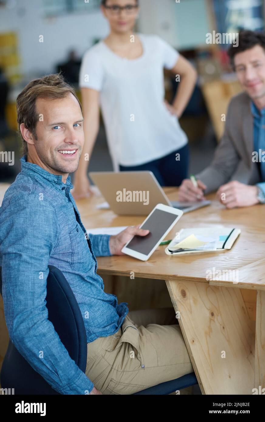Smiling marketing manager browsing the internet on a digital tablet in an office. Handsome and happy professional researching creative ideas to Stock Photo