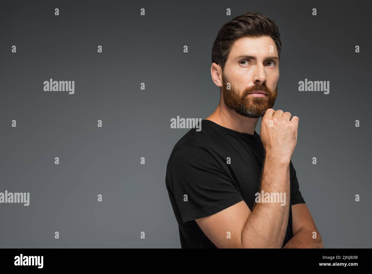 portrait of pensive man in black t-shirt looking away isolated on grey,stock image Stock Photo