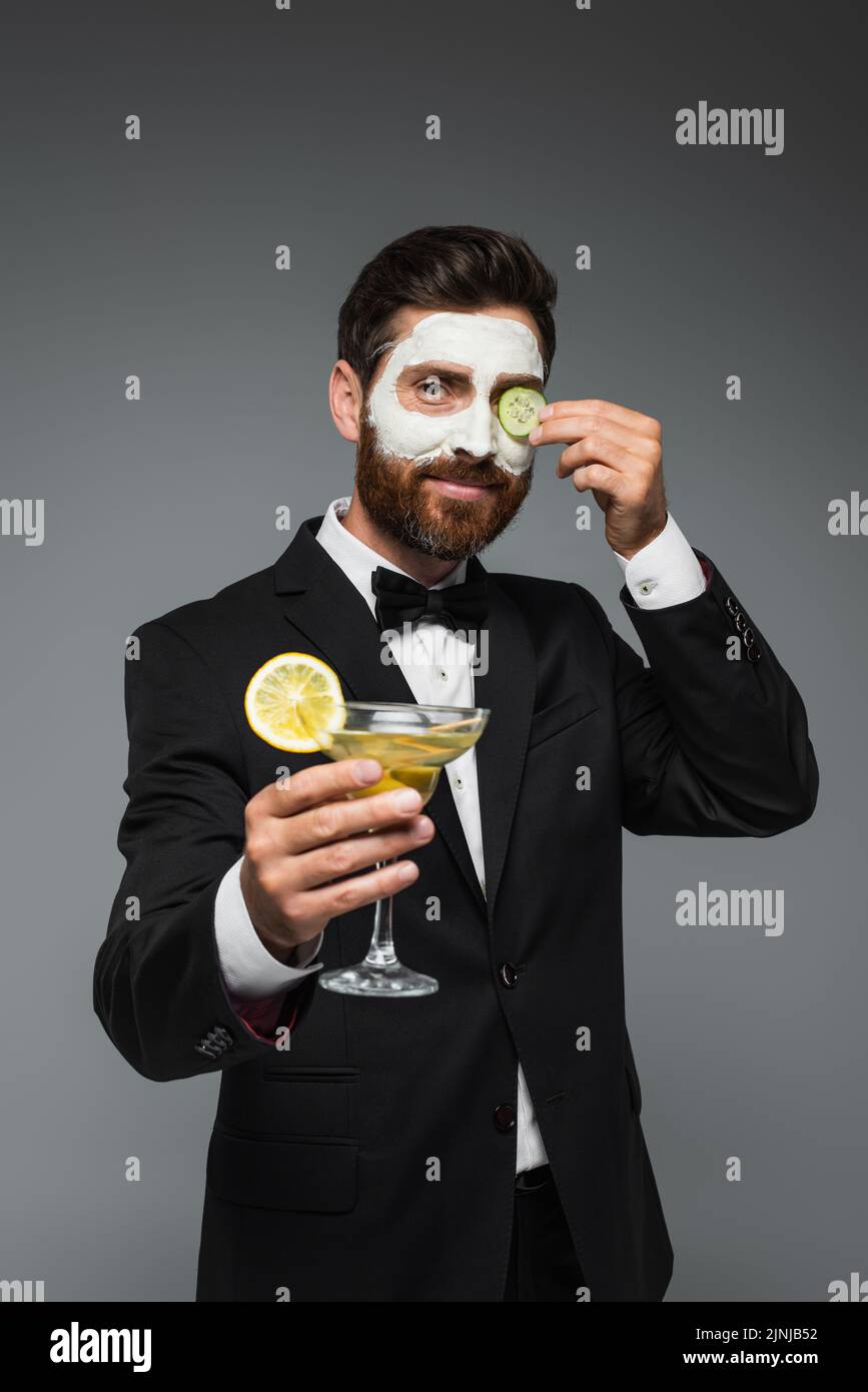 happy man in suit with clay mask on face holding cocktail isolated on grey,stock image Stock Photo