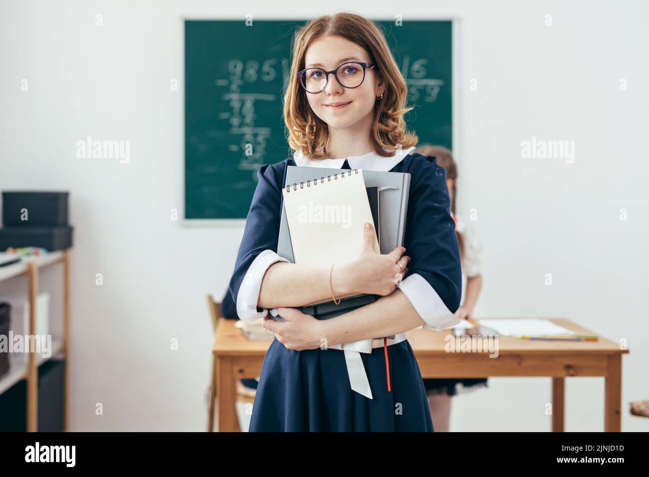 Portrait of smiling school girl with books in classroom Stock Photo - Alamy