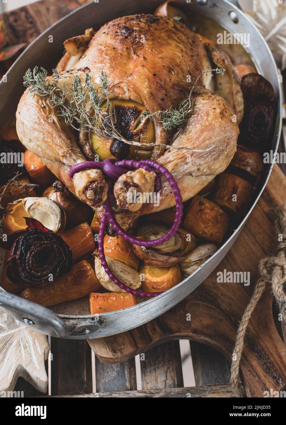 Roast whole chicken with root vegetables in a rustic roasting pan Stock