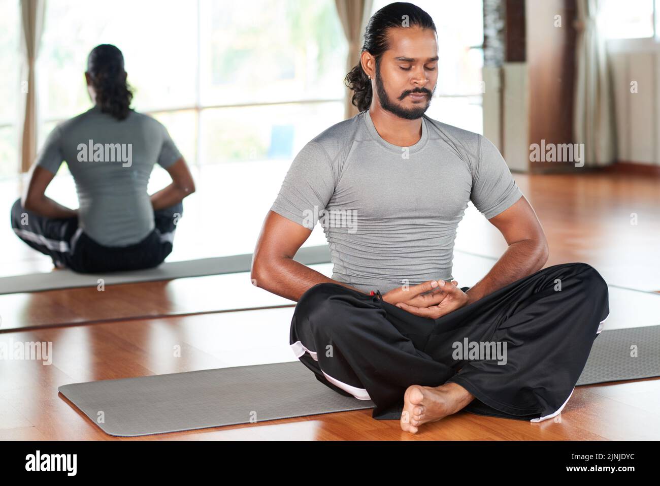 Handsome Indian man sitting in lotus position in fitness club Stock ...