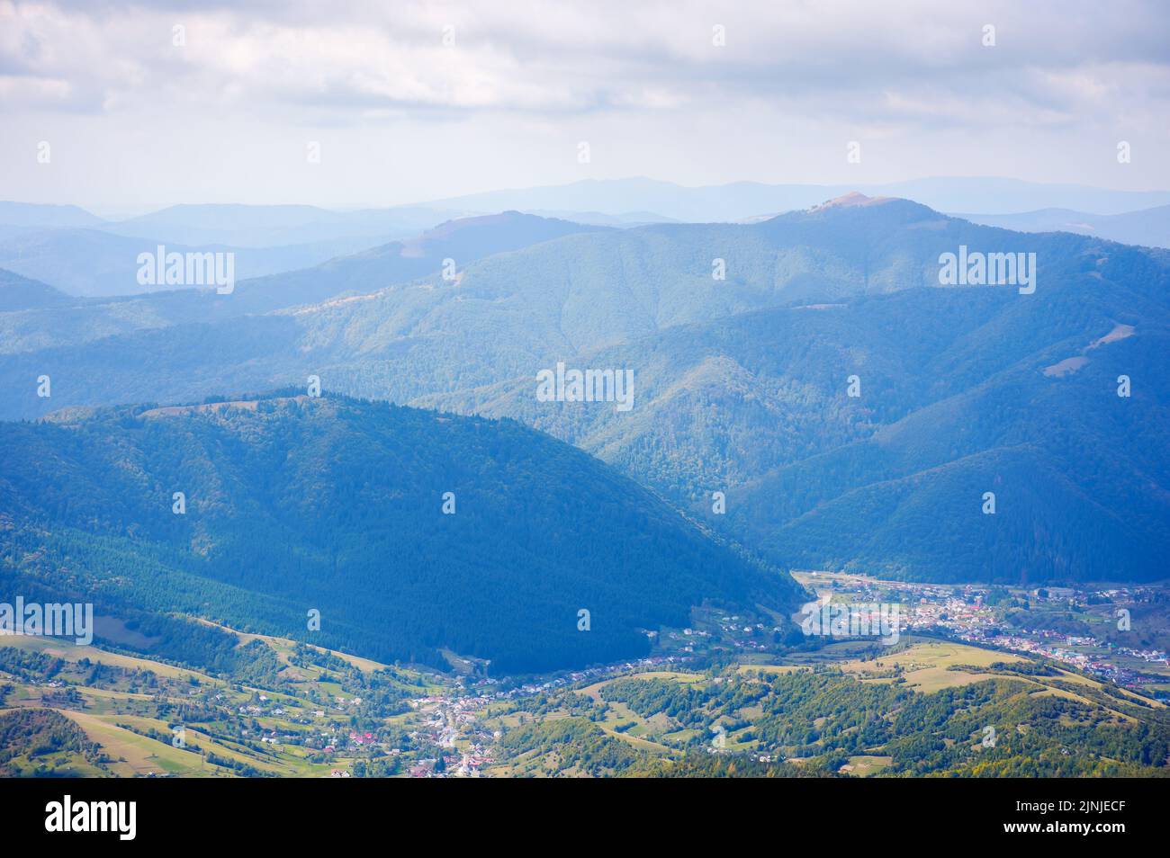 mountainous rural landscape of transcarpathia. kolochava village down in the valley observed from the top of a hill. distant ridge beneath a cloudy sk Stock Photo