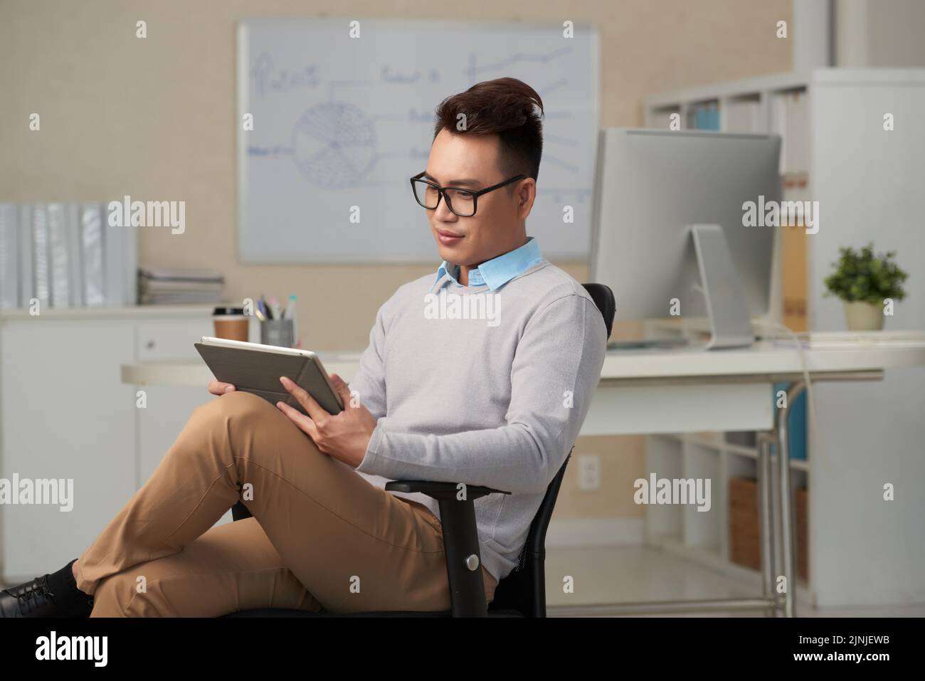 Handsome young manager reading news on tablet computer Stock Photo