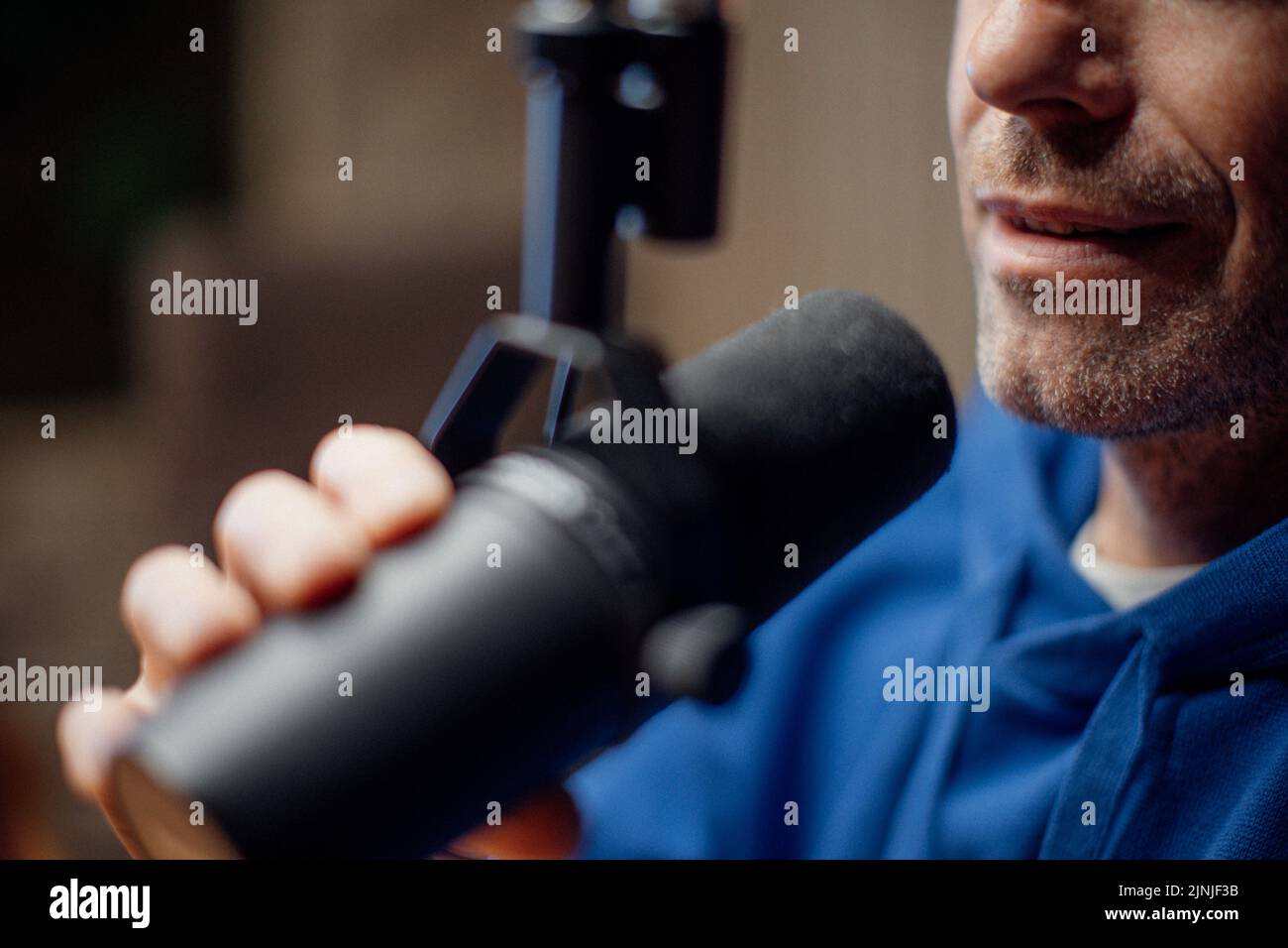 Close-up of mature man speaking in microphone during moderating podcast. Stock Photo