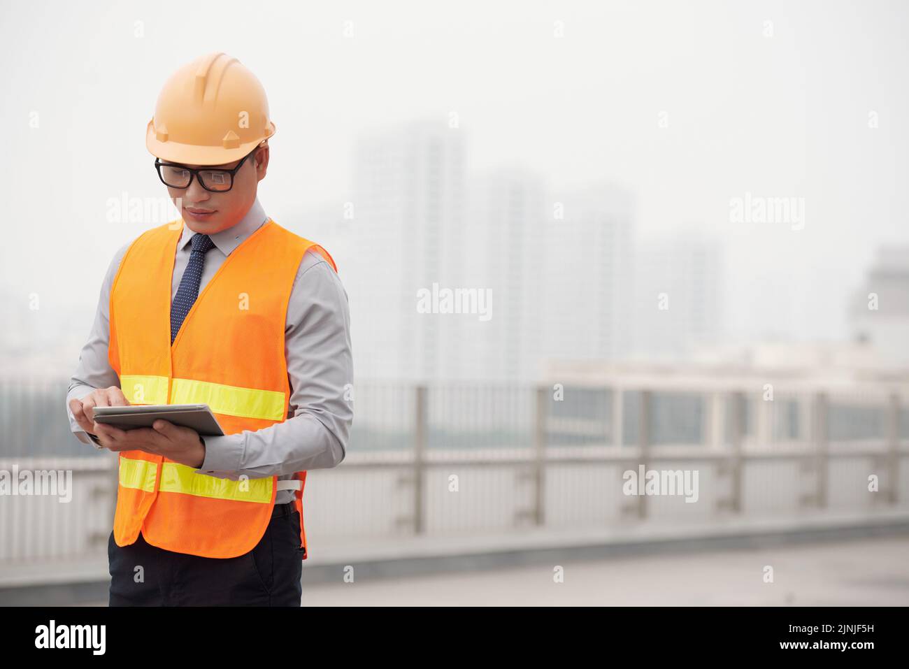Young Asian construction supervisor reading information in tablet computer Stock Photo