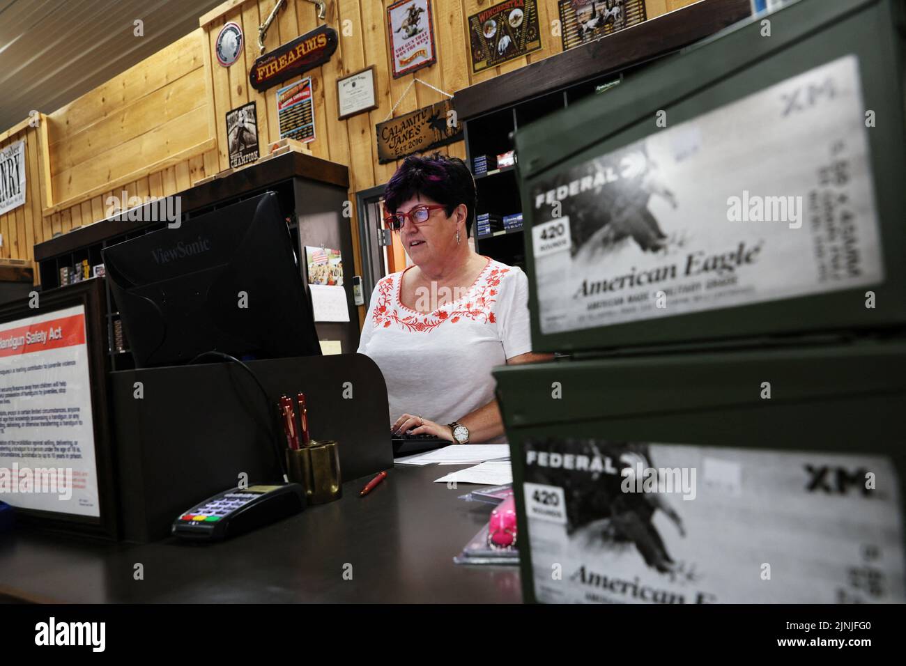 Jane Haven, manager of Calamity Jane's Firearms and Fine Shoes, works behind the counter at Calamity Jane's, in Hudson Falls, New York, U.S., July 20, 2022. REUTERS/Shannon Stapleton Stock Photo