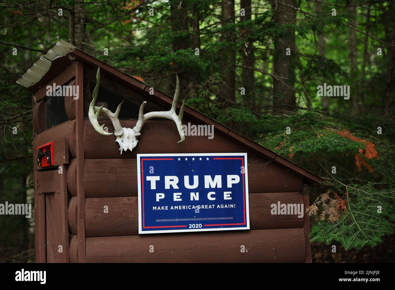 A campaign sign for former U.S. President Donald Trump and Vice President Mike Pence hangs by antlers on an outhouse at Moose Pond Club near Minerva, New York, U.S., July 20, 2022. REUTERS/Shannon Stapleton Stock Photo