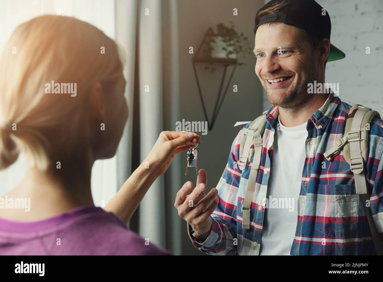 solo traveller backpacker gets keys from room owner. travel short term rent, couchsurfing Stock Photo