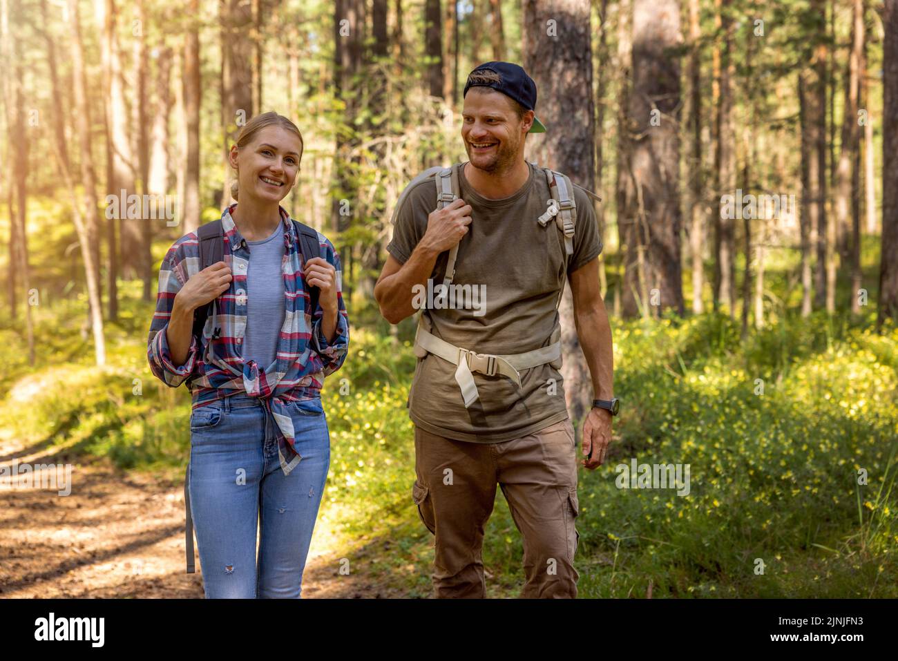young couple with backpacks on a hike in forest. backpacking trip, summer adventure vacation Stock Photo