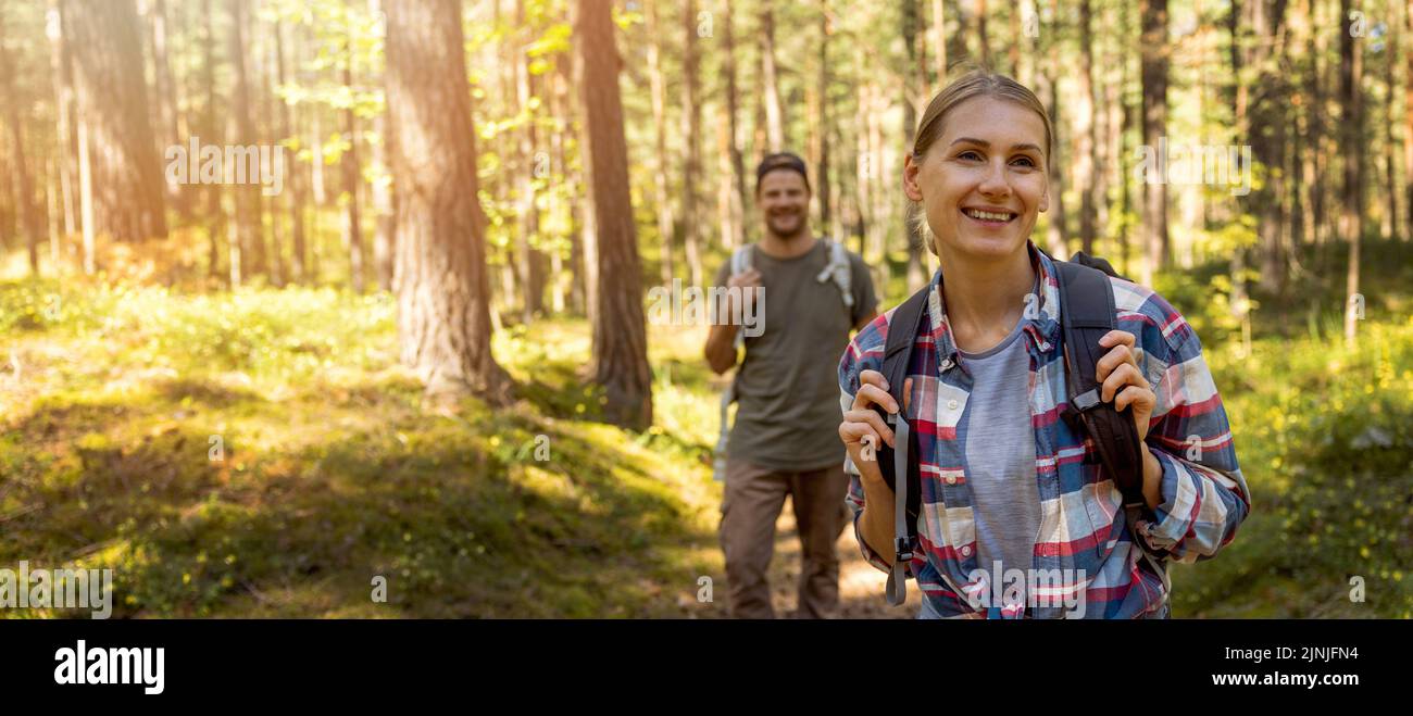 young travel couple with backpacks on nature adventure hike in forest. banner with copy space Stock Photo
