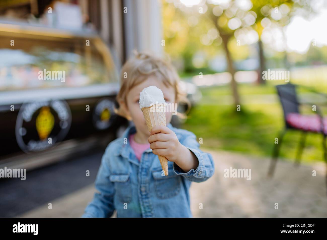 Little girl enjoying ice cream in park during hot summer day. Stock Photo