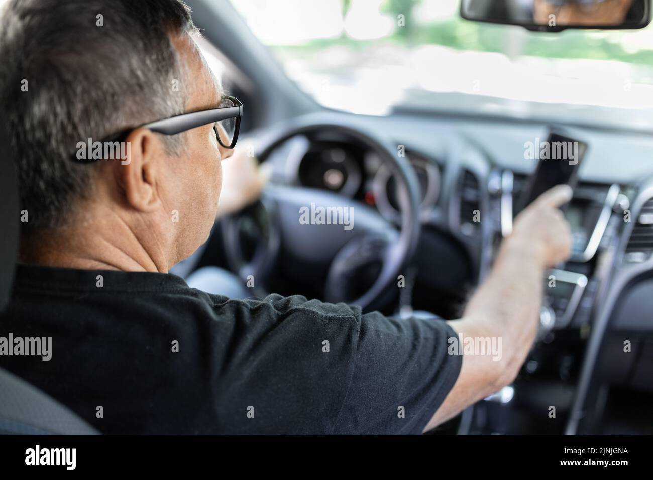 Senior behind the steering wheel using navigation and looking for directions Stock Photo