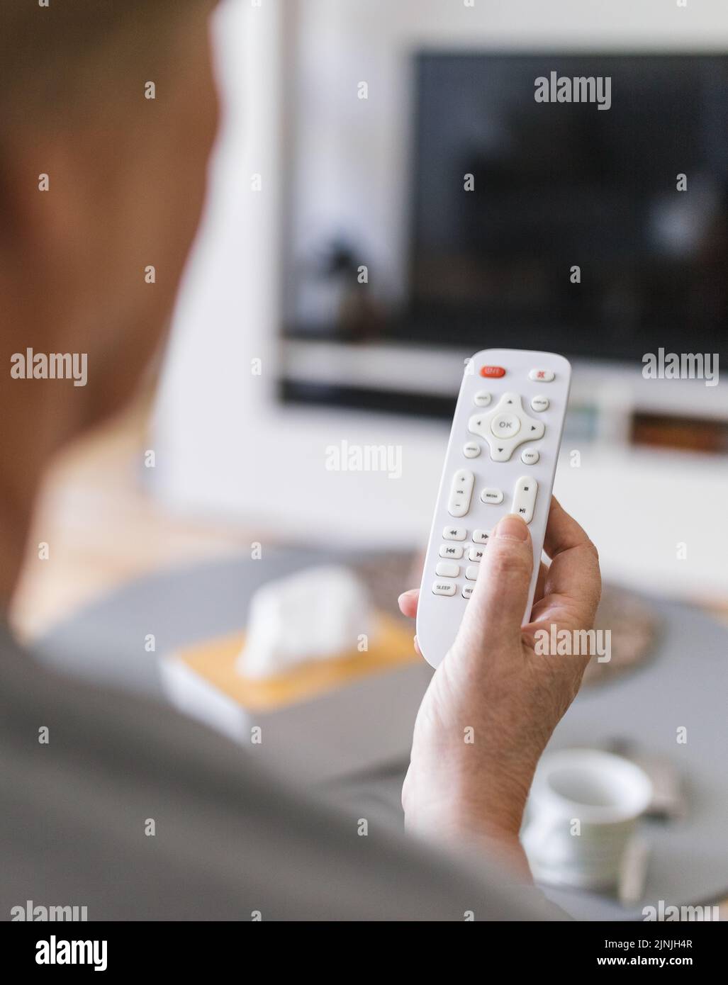 Senior woman with remote control watching television Stock Photo - Alamy