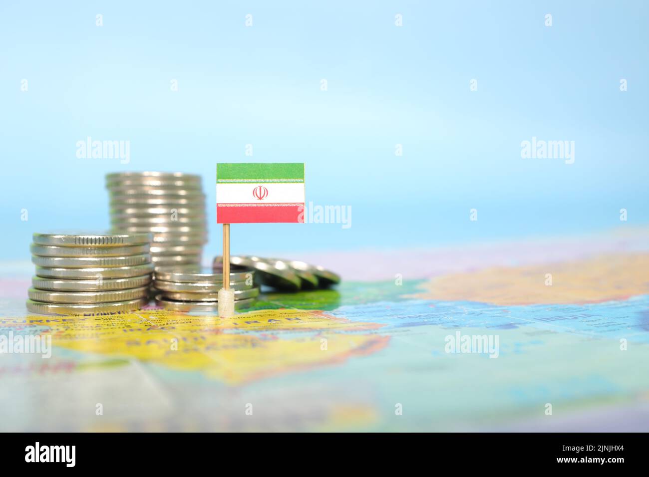 Selective focus of Iranian flag in blurry world map with coins. Iran economy and wealth concept. Stock Photo