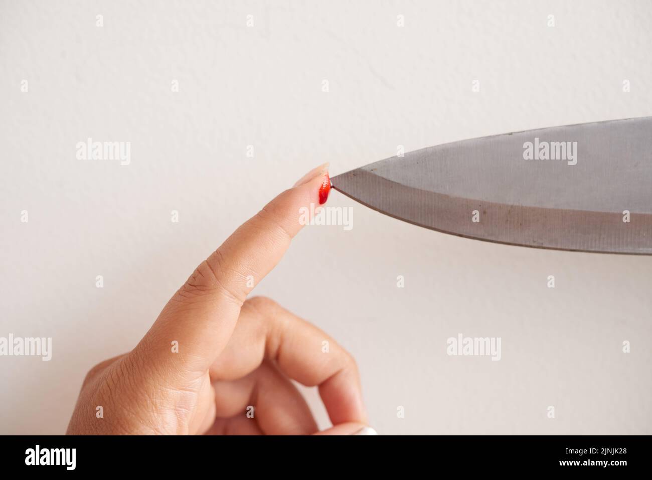 Closeup shot of female finger with bleeding cut checking sharpness of