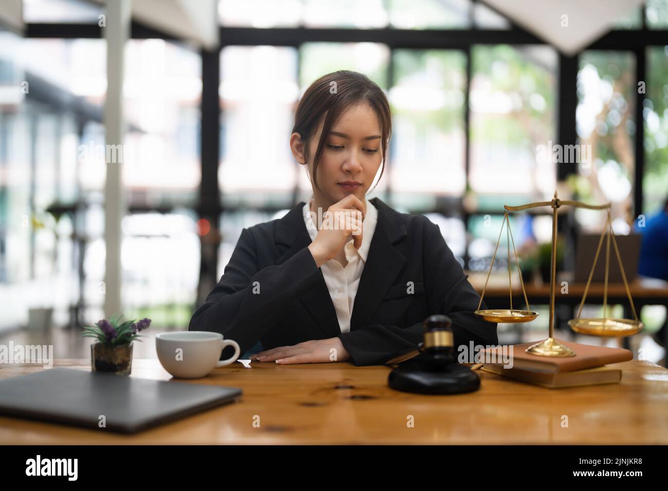 Thinking woman lawyers discussing contract papers with brass scale in
