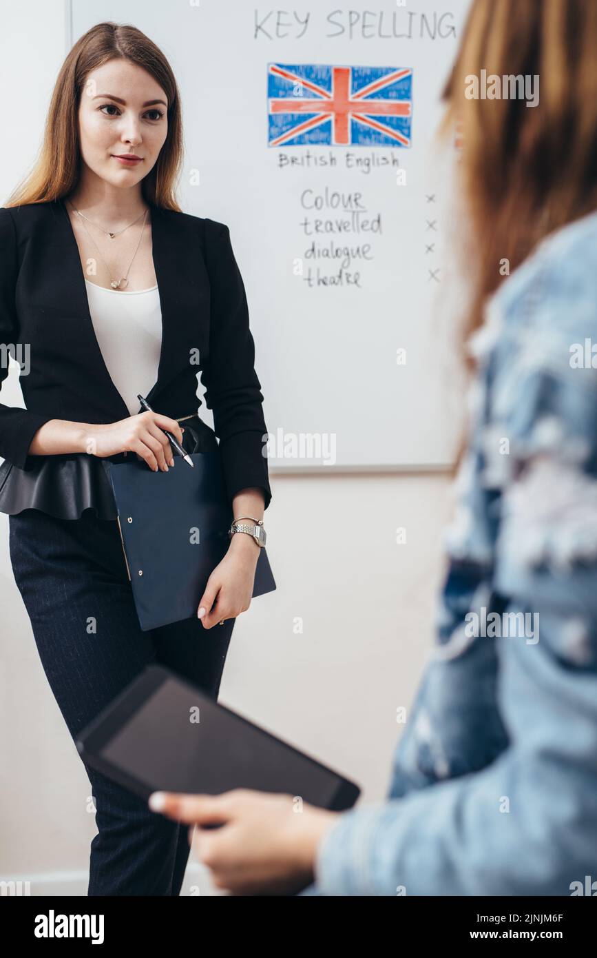 Two female students talking in classroom. College, English language school Stock Photo