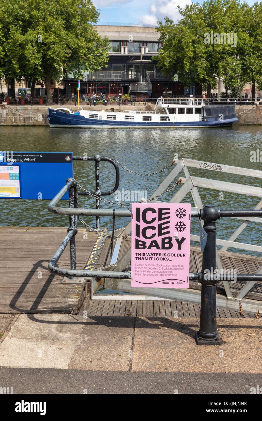 Pink notice warning of the danger of jumping into cold dock water, Bristol harbourside, Wapping Wharf , City of Bristol, England, UK Stock Photo