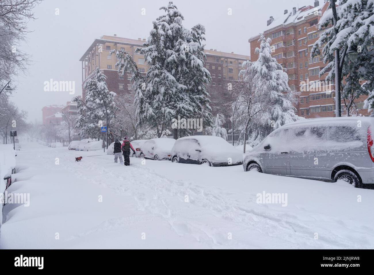 Streets and buildings covered in snow by day due to snowstorm Filomena falling in Madrid Spain. People walking in the snow. spain Stock Photo