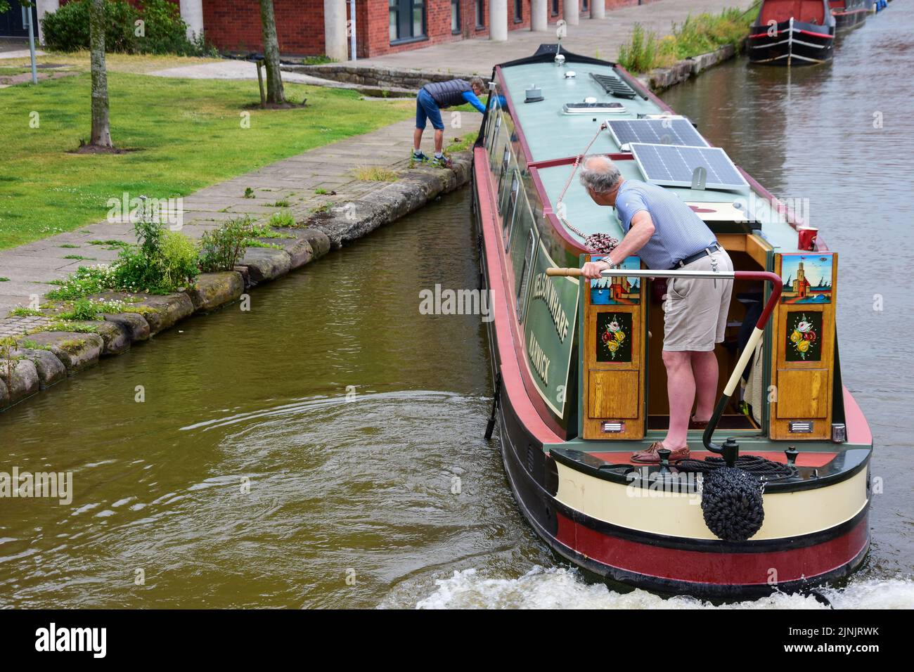 Chester, UK: Jul 3, 2022: A couple carefully manoeuvre their narrowboat in the Chester Canal Basin of the Shropshire Union Canal Stock Photo