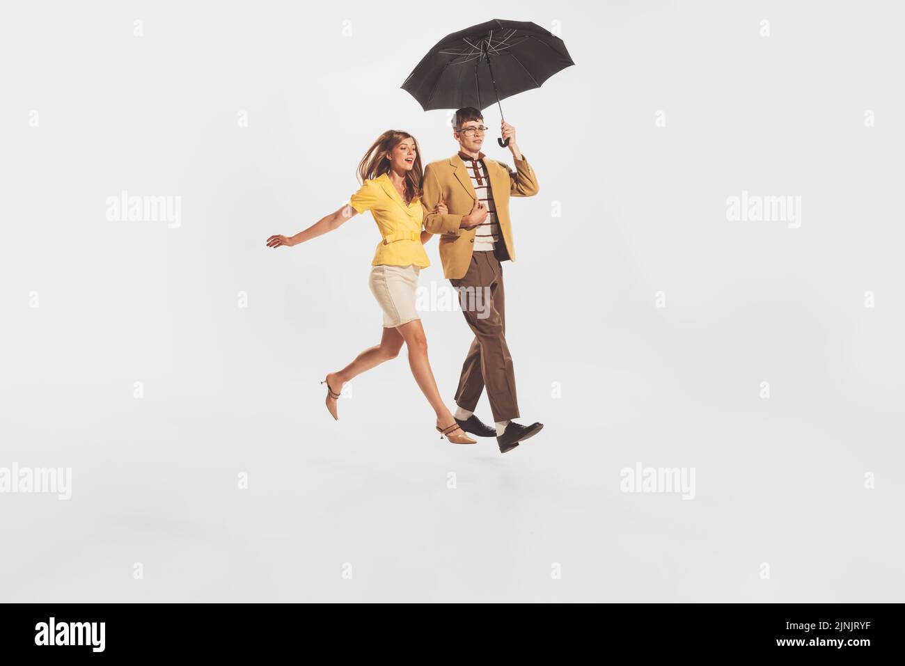 Portrait of young stylish couple, man and woman walking under umbrella ...