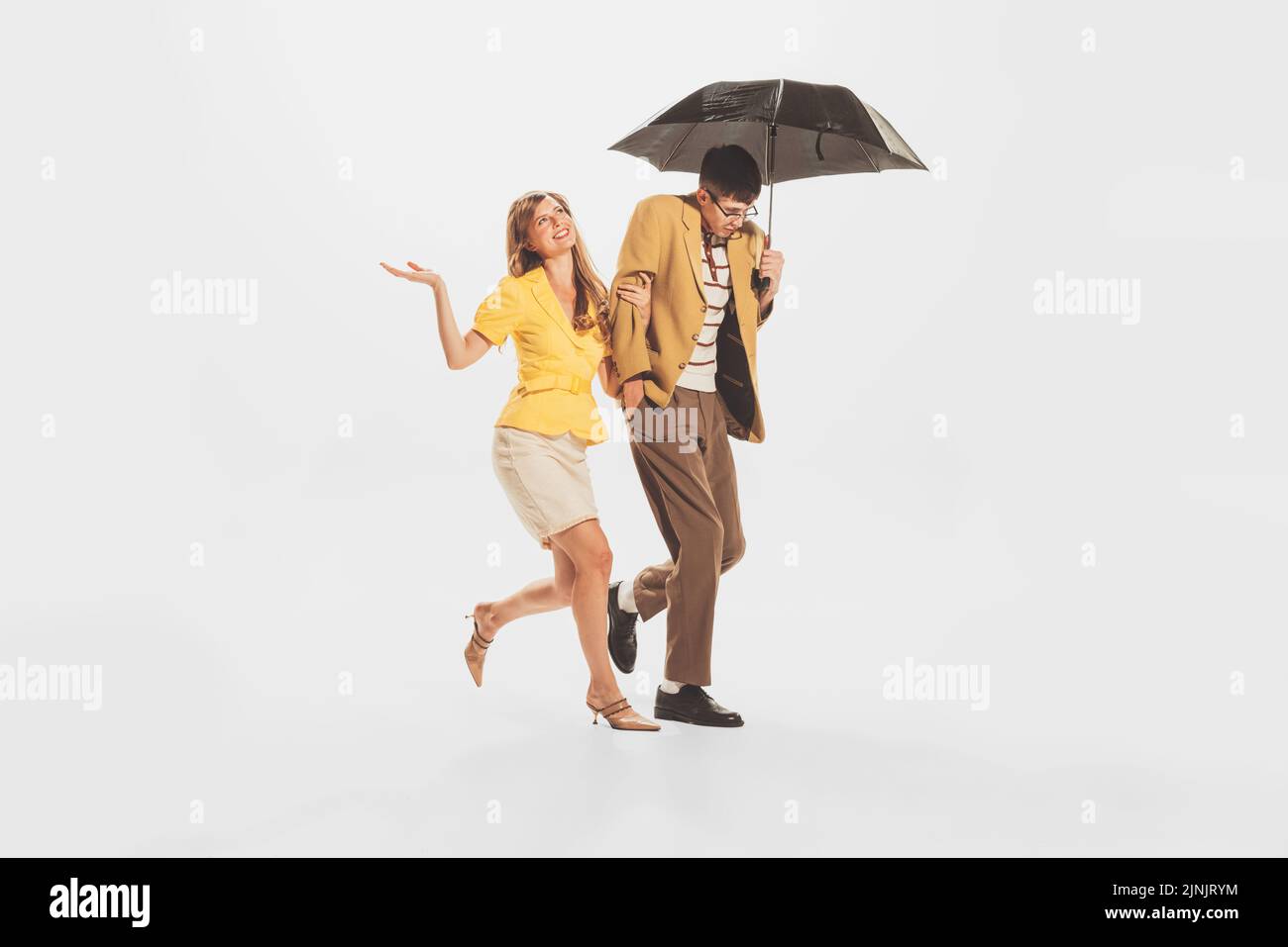 Portrait of young stylish couple, man and woman walking under umbrella ...
