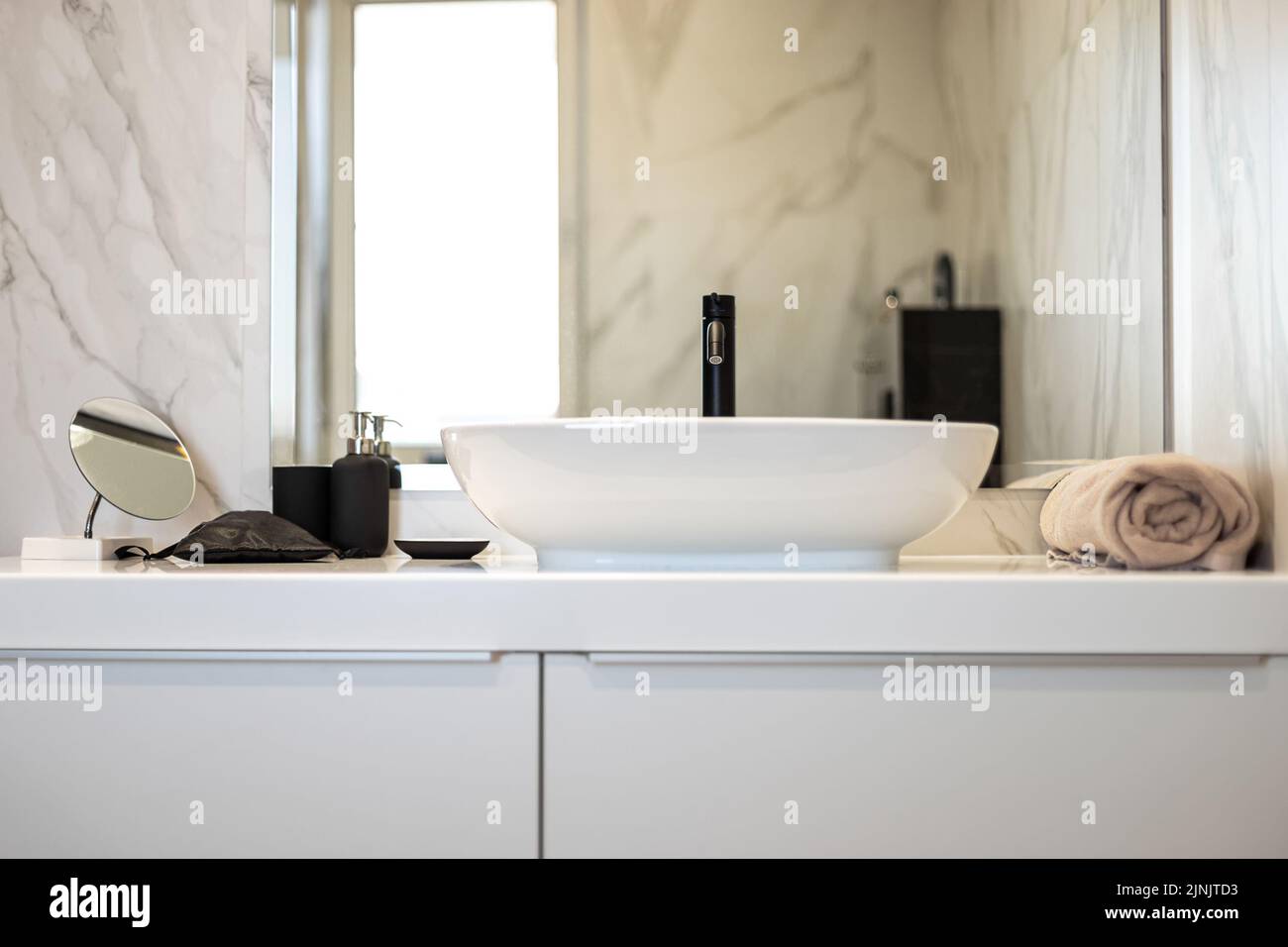 Modern washbasin with black faucet beside a stylish soap dispenser. Stock Photo