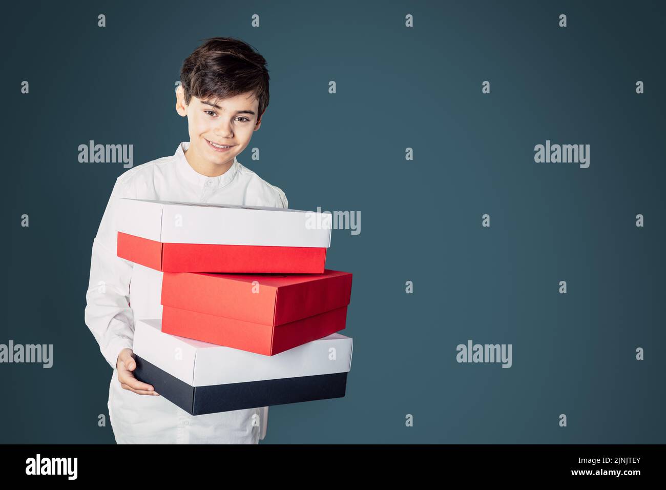 A handsome teen boy with red and white coloured present boxes holding ...