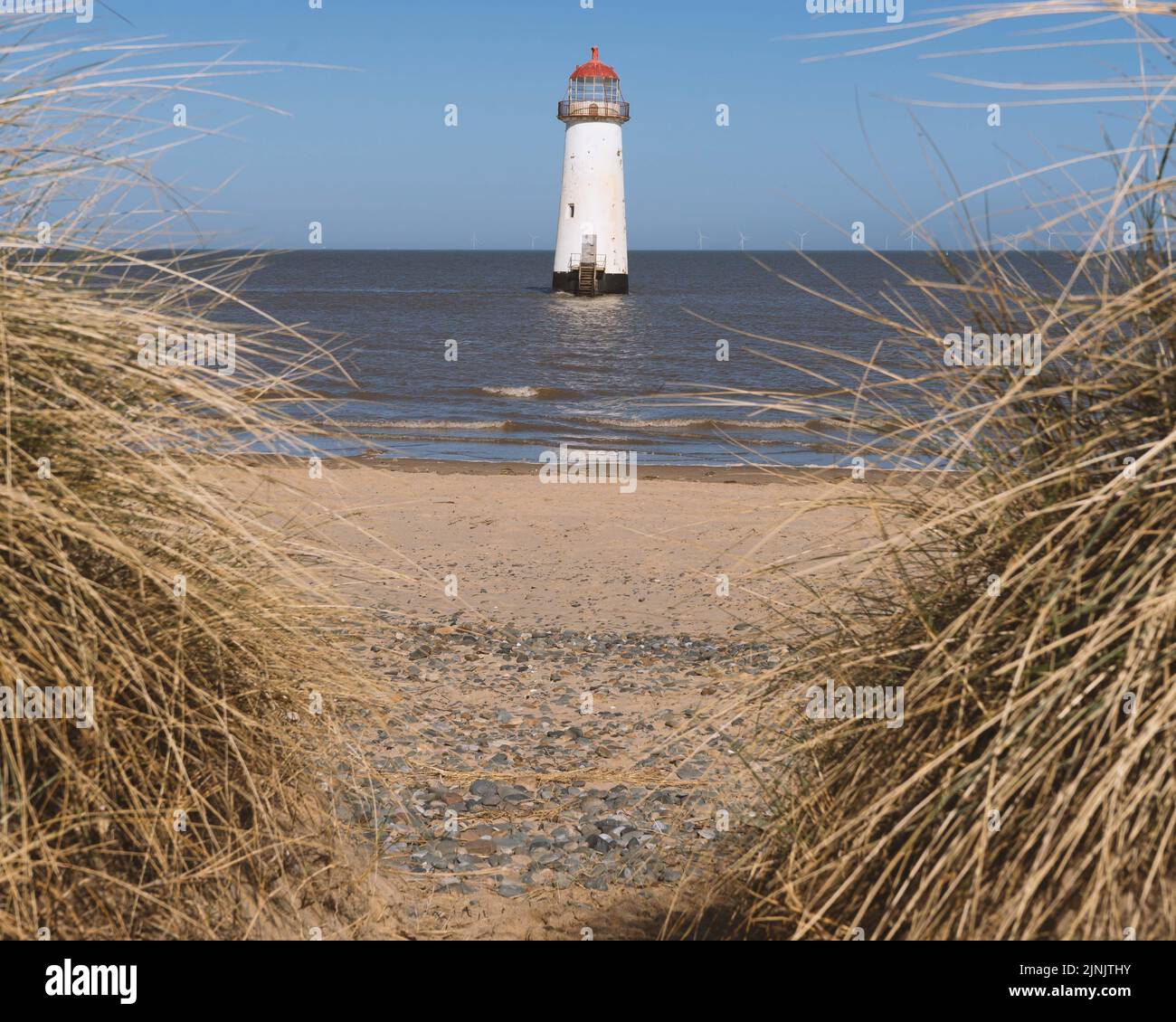 The Point of Ayr Lighthouse in Wales visible from the dry grass area
