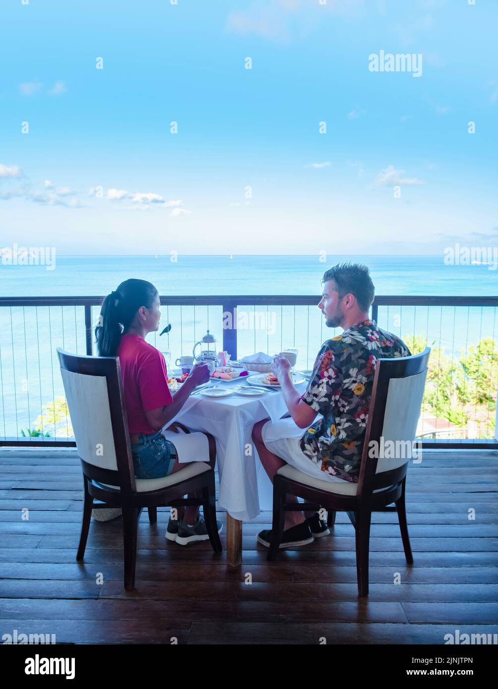 couple men and women having breakfast with a look over the ocean of