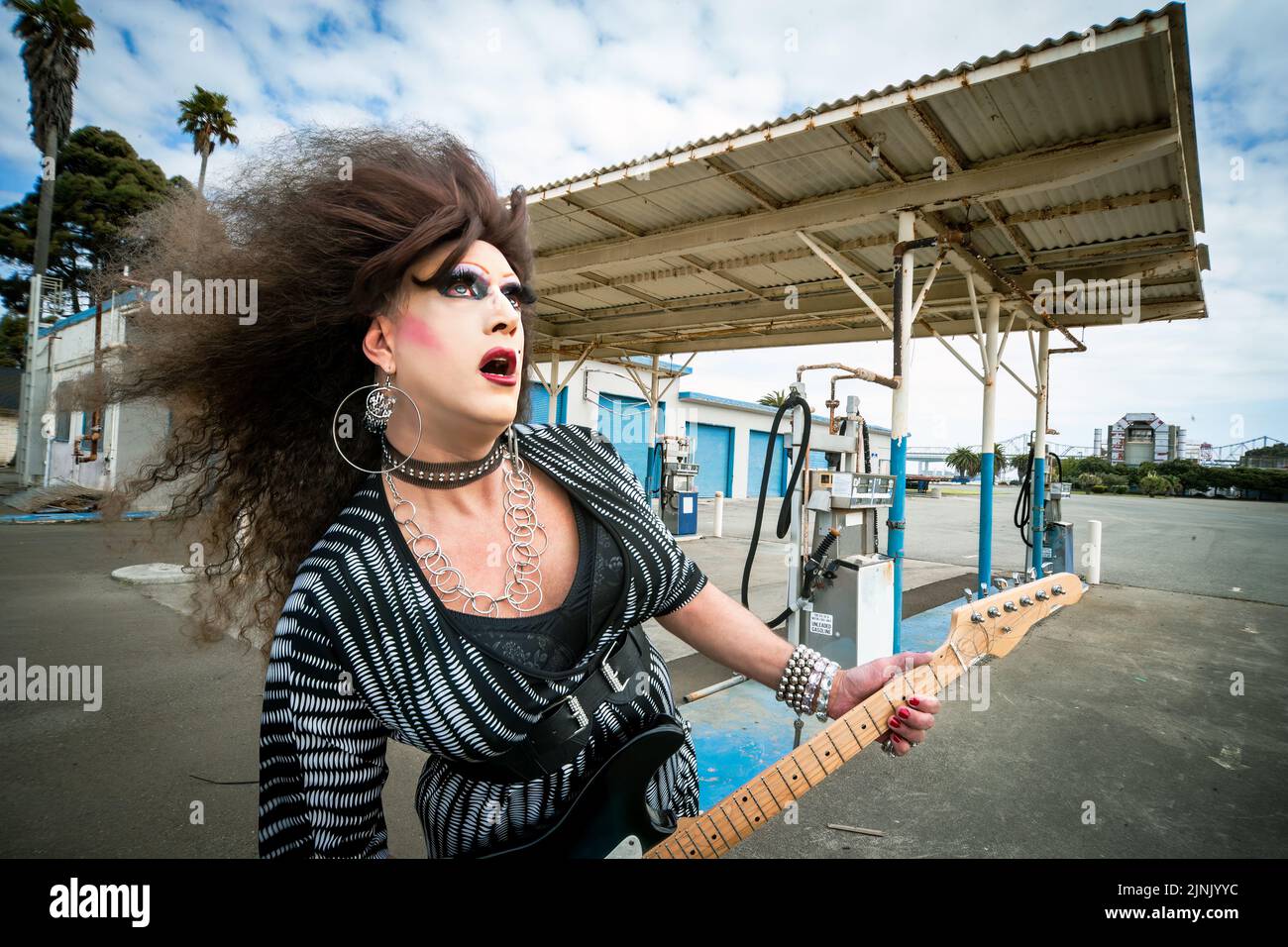 portrait of drag queen rocker with big wig playing the guitar Stock Photo