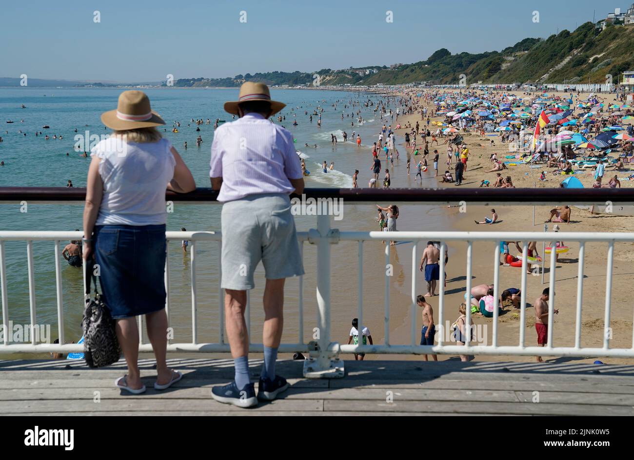 Two people look out from Bournemouth pier as people gather in the hot weather at Bournemouth beach in Dorset. A drought is set to be declared for some parts of England on Friday, with temperatures to hit 35C making the country hotter than parts of the Caribbean. Picture date: Friday August 12, 2022. Stock Photo