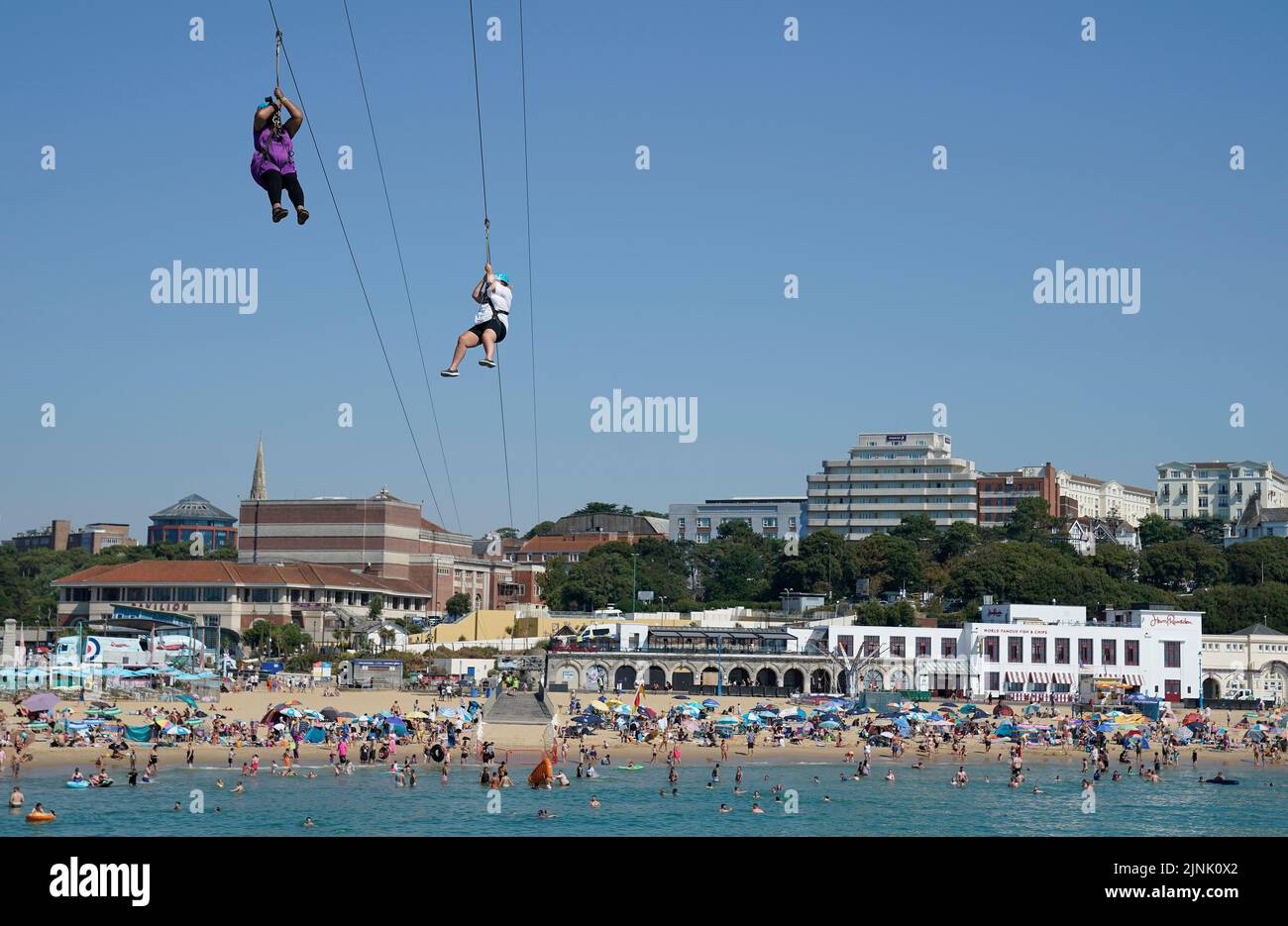 Two people zip line from Bournemouth pier towards Bournemouth beach in Dorset. A drought is set to be declared for some parts of England on Friday, with temperatures to hit 35C making the country hotter than parts of the Caribbean. Picture date: Friday August 12, 2022. Stock Photo