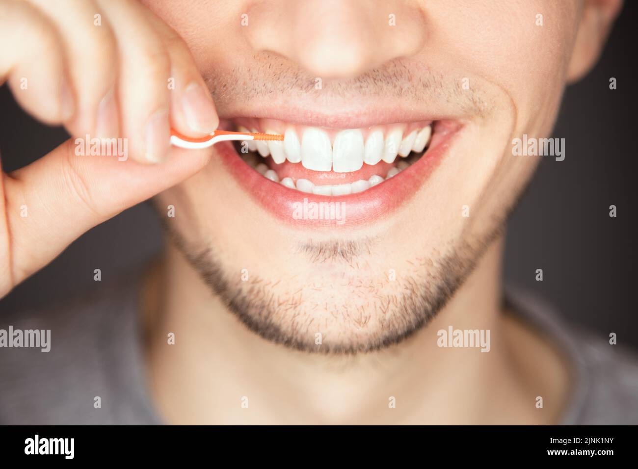 A male cleaning and flossing space between tooth with plastic and
