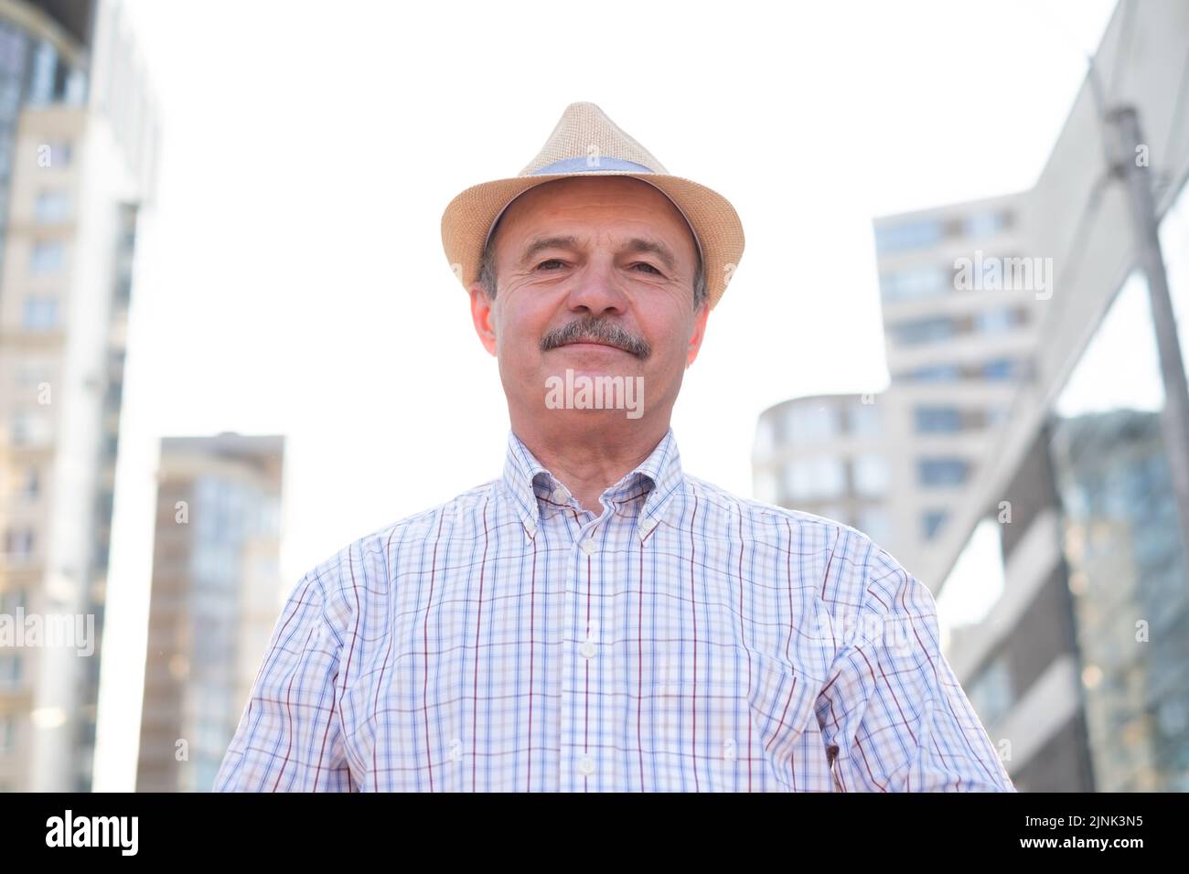 Ethnic senior man wearing hat walking outdoors in the city Stock Photo