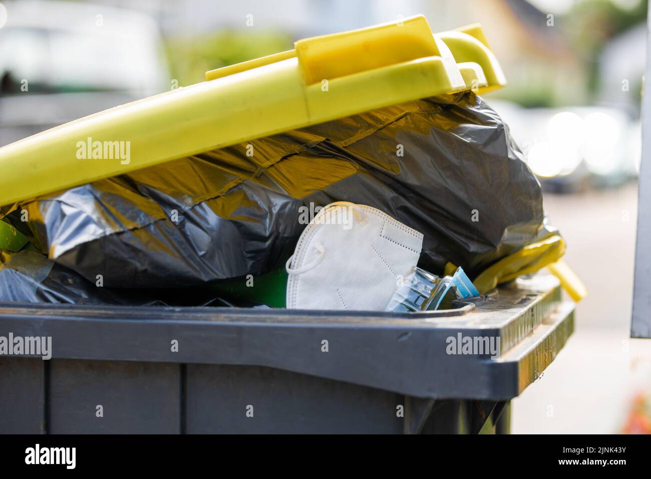 A full garbage trash can with ffp2 face mask standing at sidewalk Stock ...