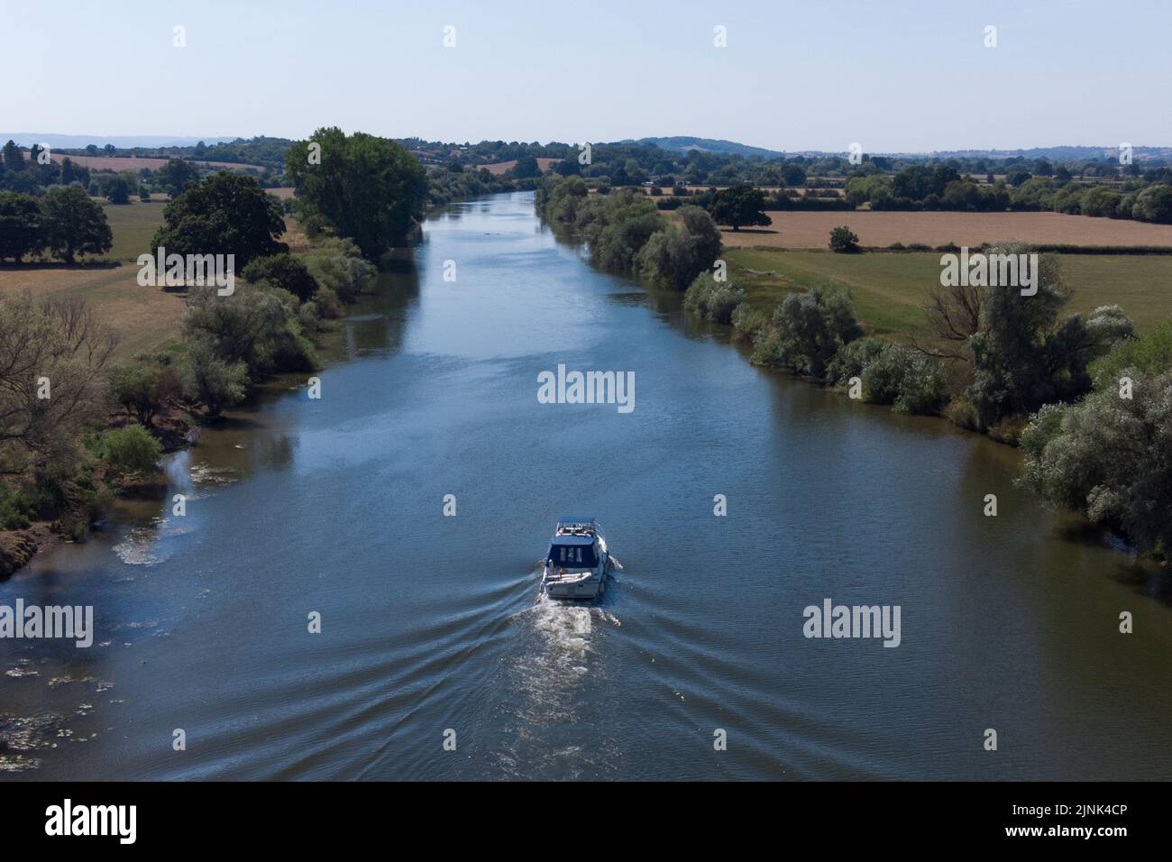 Forthampton, Gloucestershire August 12th 2022 - A boat navigates down the River Severn near Tewkesbury in Gloucestershire, England during the heatwave. Credit: SCOTT CM/Alamy Live News Stock Photo