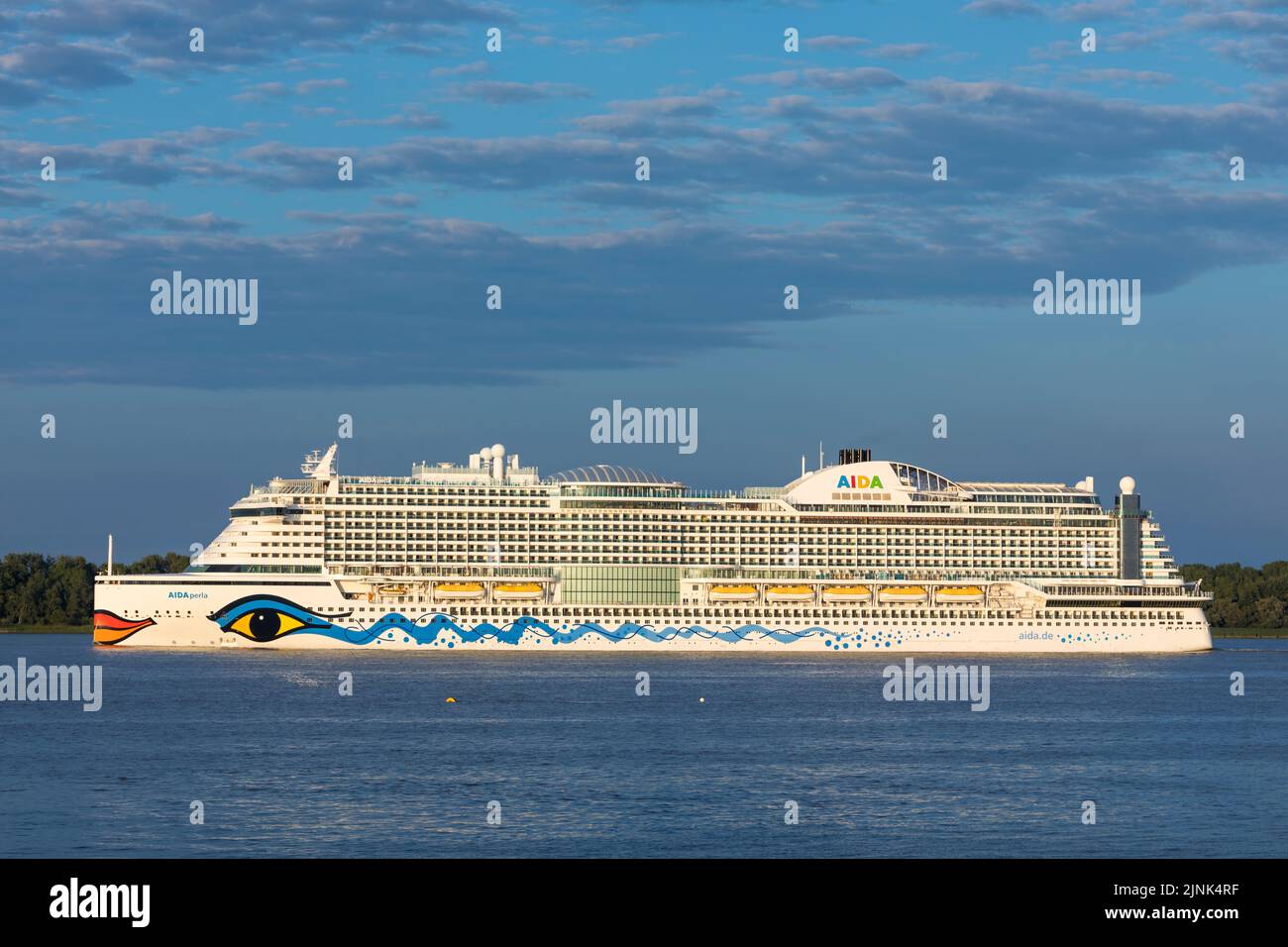 Stade, Germany – August 7, 2022: Cruise ship AIDAPerla, owned by Carnival Corporation, leaving Hamburg on Elbe river at dusk Stock Photo