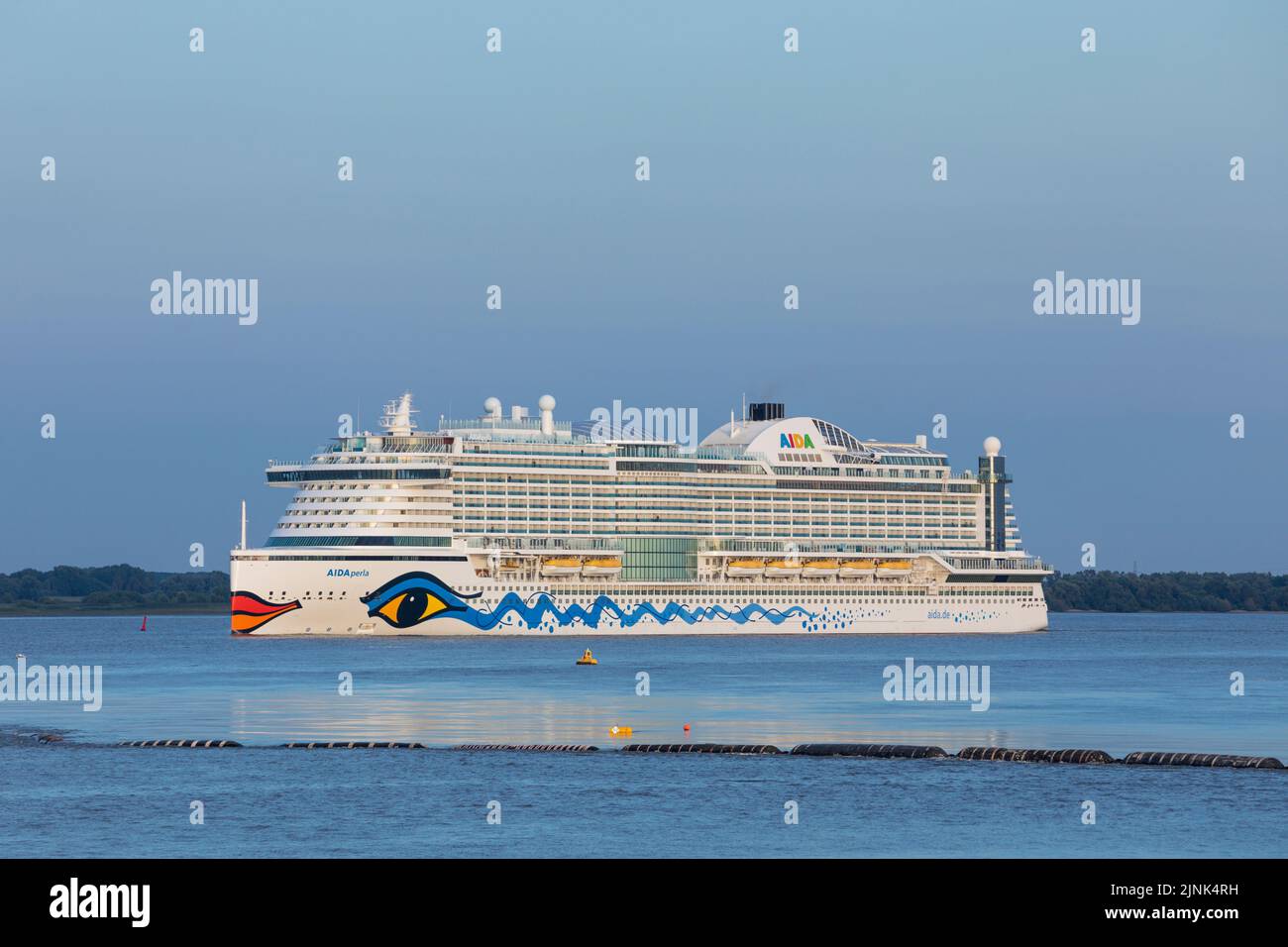 Stade, Germany – August 7, 2022: Cruise ship AIDAPerla, owned by Carnival Corporation, leaving Hamburg on Elbe river at dusk Stock Photo