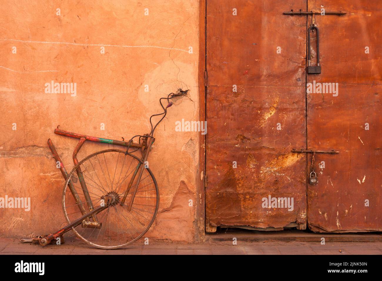 Leftovers of bicycle fixed to wall next to rusty door in Marrakesh, Morocco Stock Photo